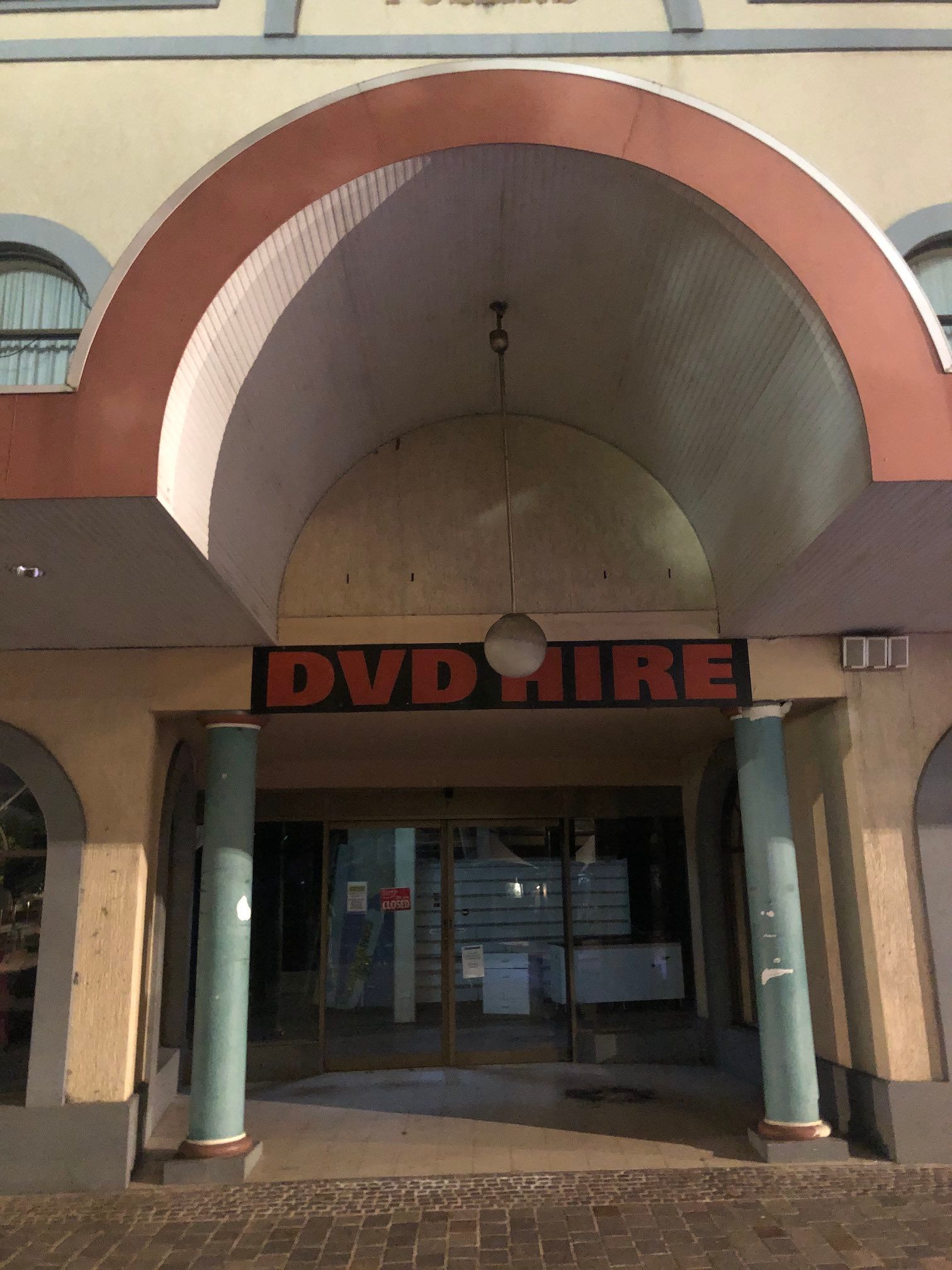 Ex-DVD Hire shop, now for lease, with columns and oversized arch above entrance.