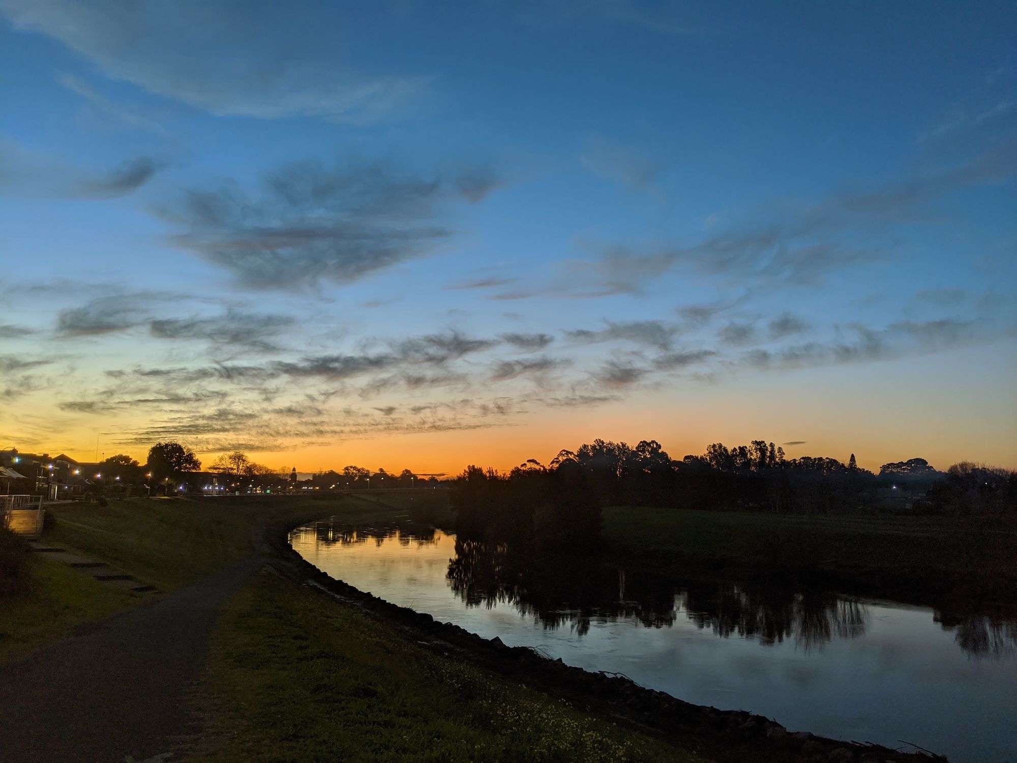 River foreground, sunset background, path on the left of the river.