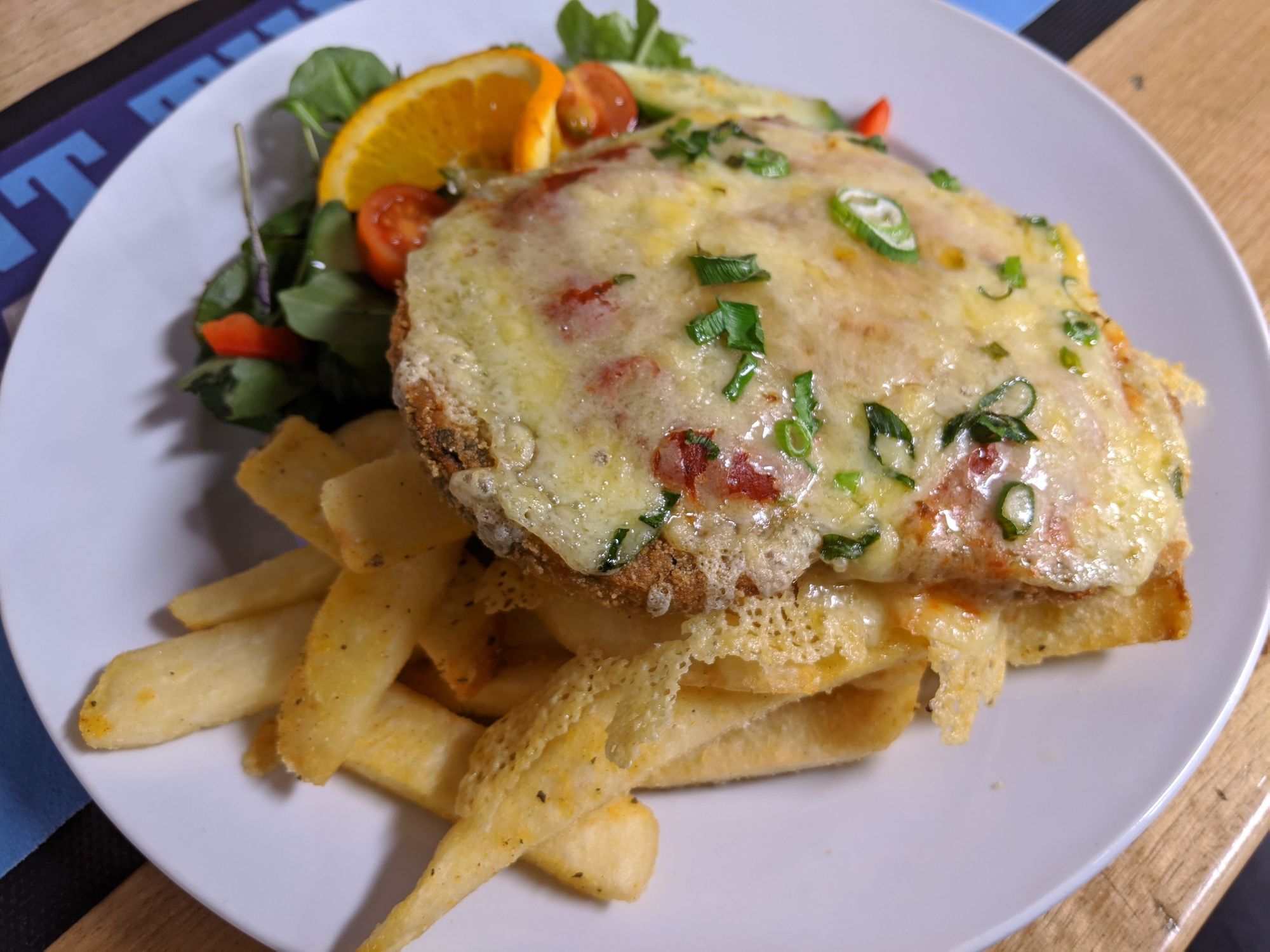 Vegetarian Parmigiana on plate with salad and chips.